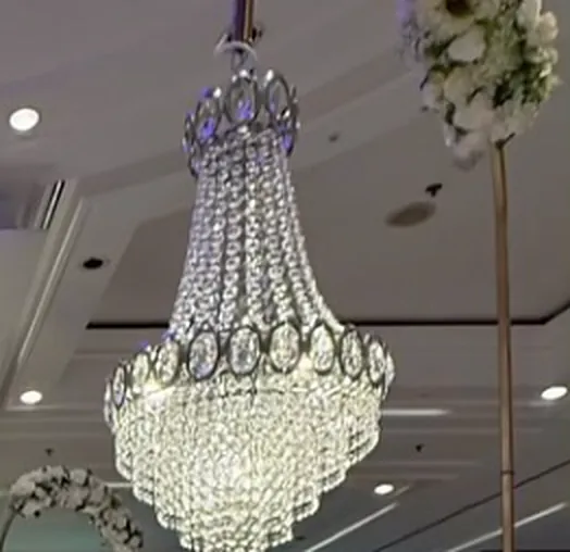 A crystal chandelier and white floral arch styled by Kyra Events in a hotel ballroom