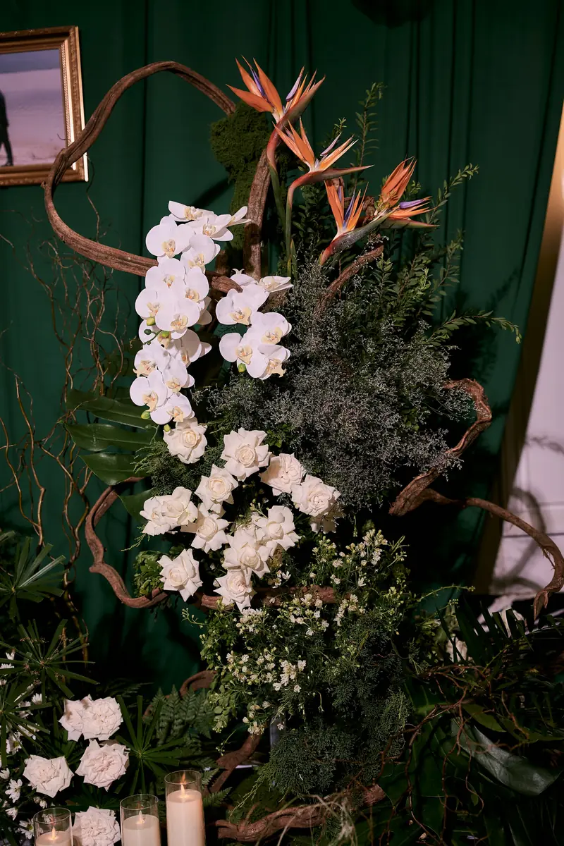 White orchids and deep green foliage arranged beside lit candles