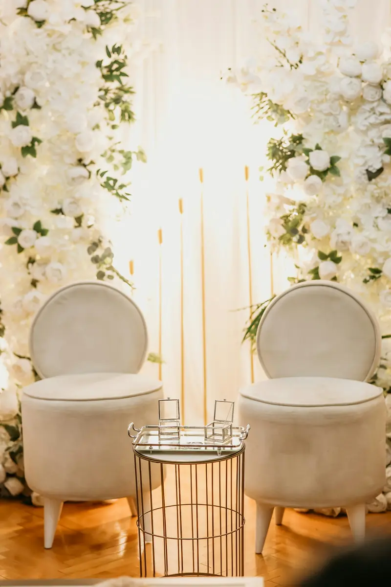 Two ivory chairs framed by walls of white flowers