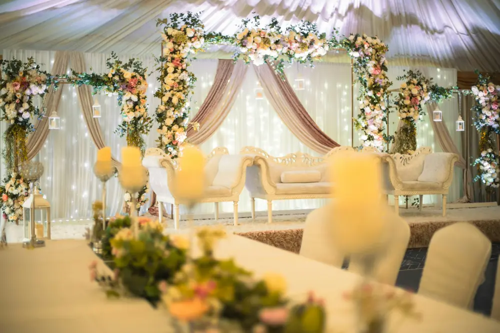 An ivory stage with carved sofas, floral arches and soft drapery
