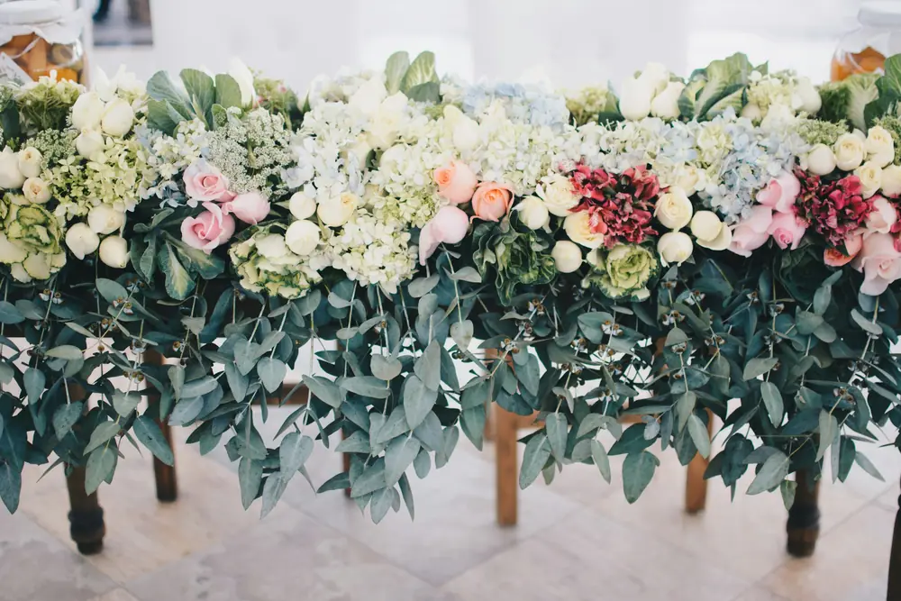 A dense floral runner of white and blush roses over silver-green eucalyptus