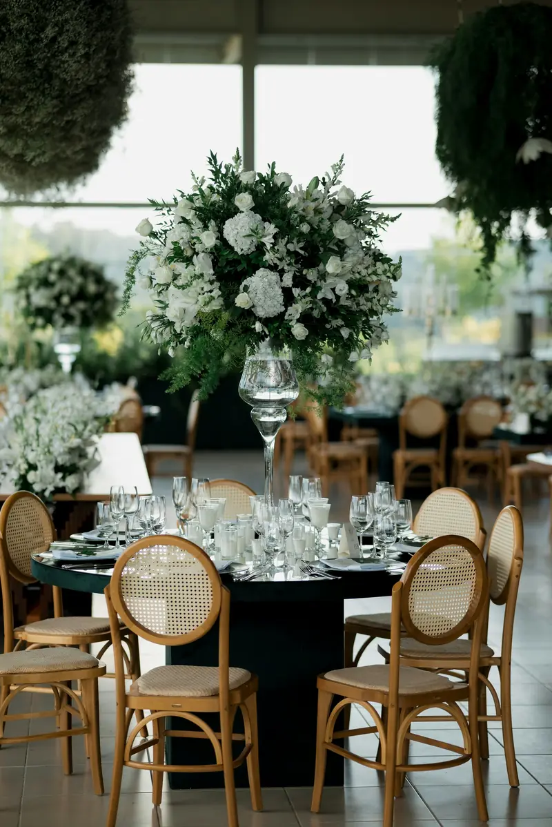 A tall white floral centrepiece above a dressed reception table