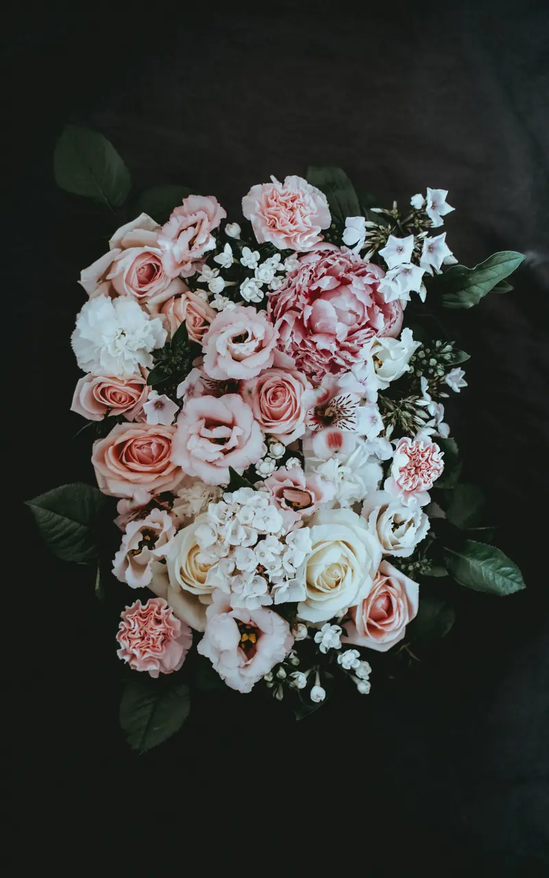 A cascading arrangement of blush and ivory roses against a dark background