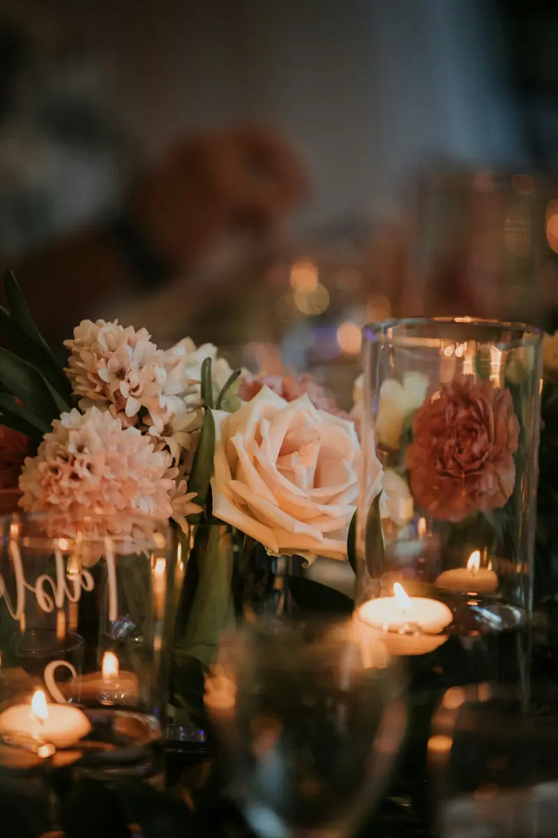 Blush roses and dahlias beside glass votives glowing with candlelight